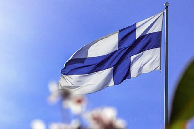 Suomen lippu liehuu tuulessa. Alentaja levitteet on valmistettu Suomessa