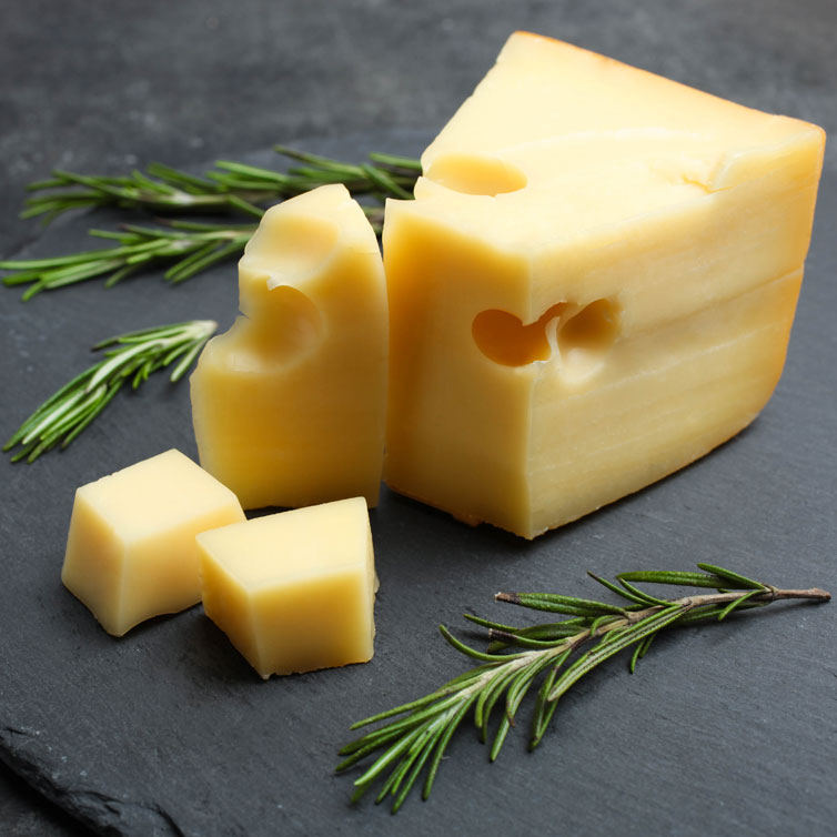 Muutama pala juustoa takaa päivittäisen kalsiumin saannin. Kuva juustosta tummanharmaalla alustalla.